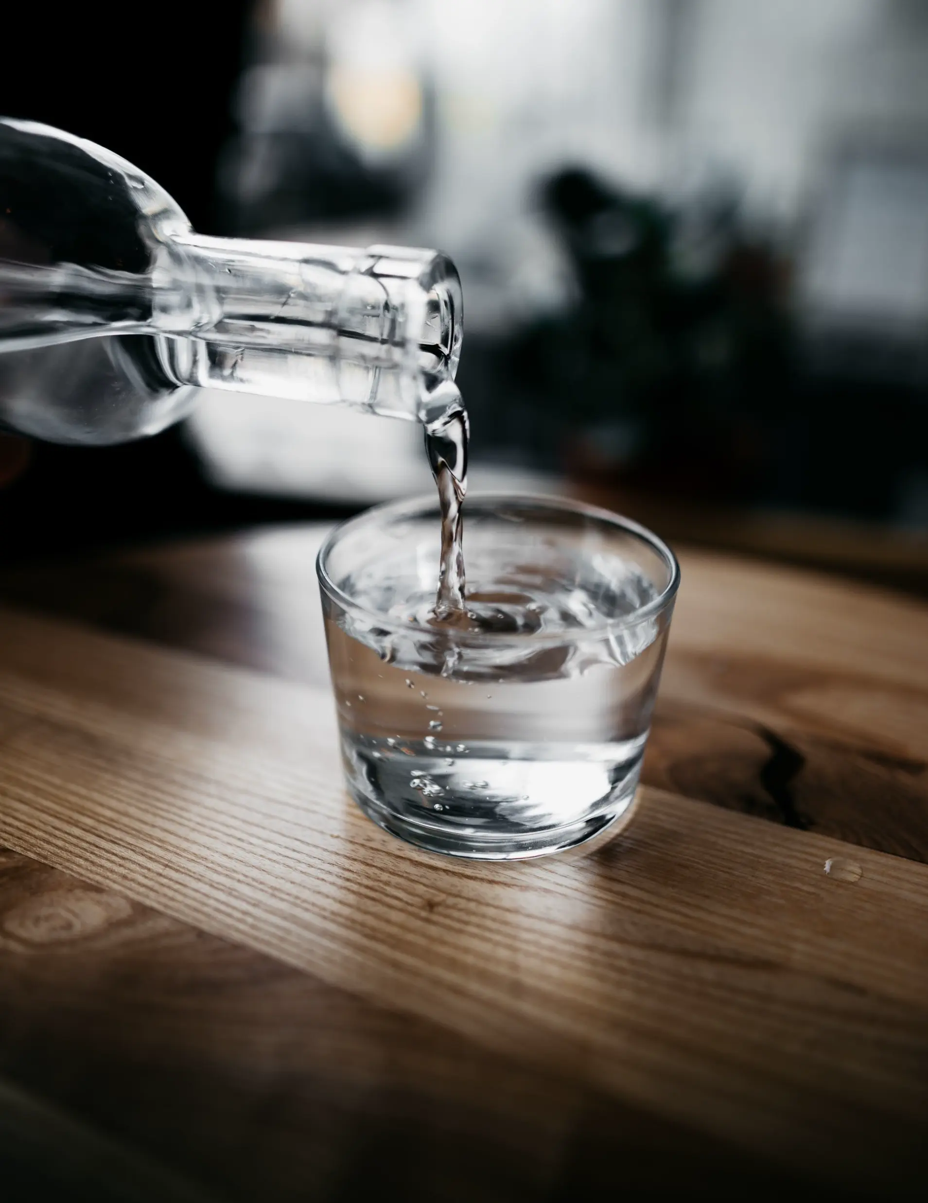 bouteille qui remplit un verre d'eau à moitié plein